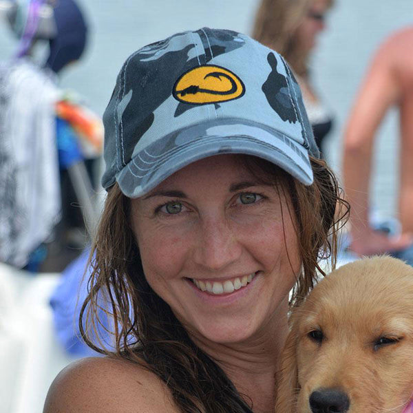 young woman in a Hook Life Water Camo fishing cap holding a puppy