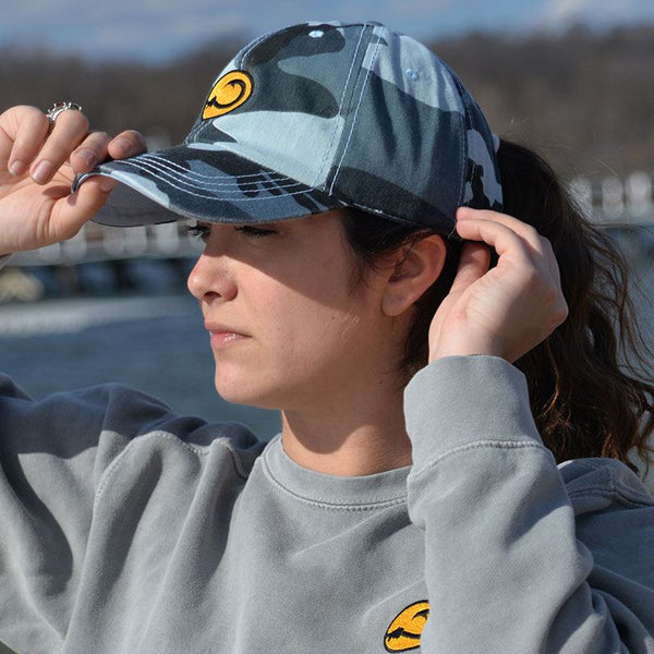 young woman wearing Water Camo fishing cap by Hook Life at a harbor