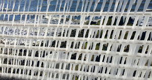 breaking waves viewed through icicles on a boardwalk railing