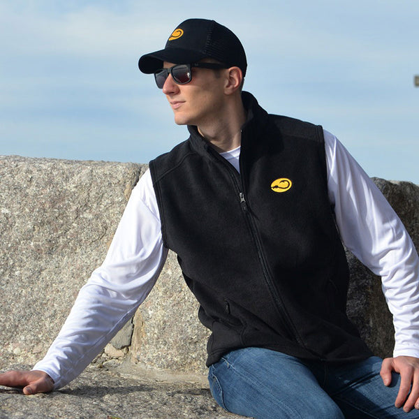 young man in black Fishers Fleece Vest by Hook Life on a sea wall