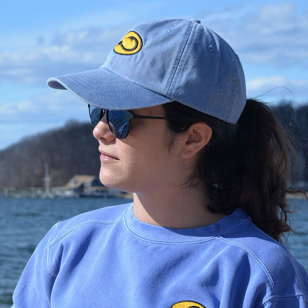 young woman wearing blue Beach fishing cap by Hook Life at a harbor