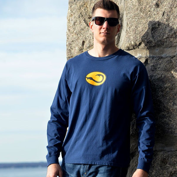 young man wearing  navy long sleeve Hook Life tee shirt on a sea wall 
